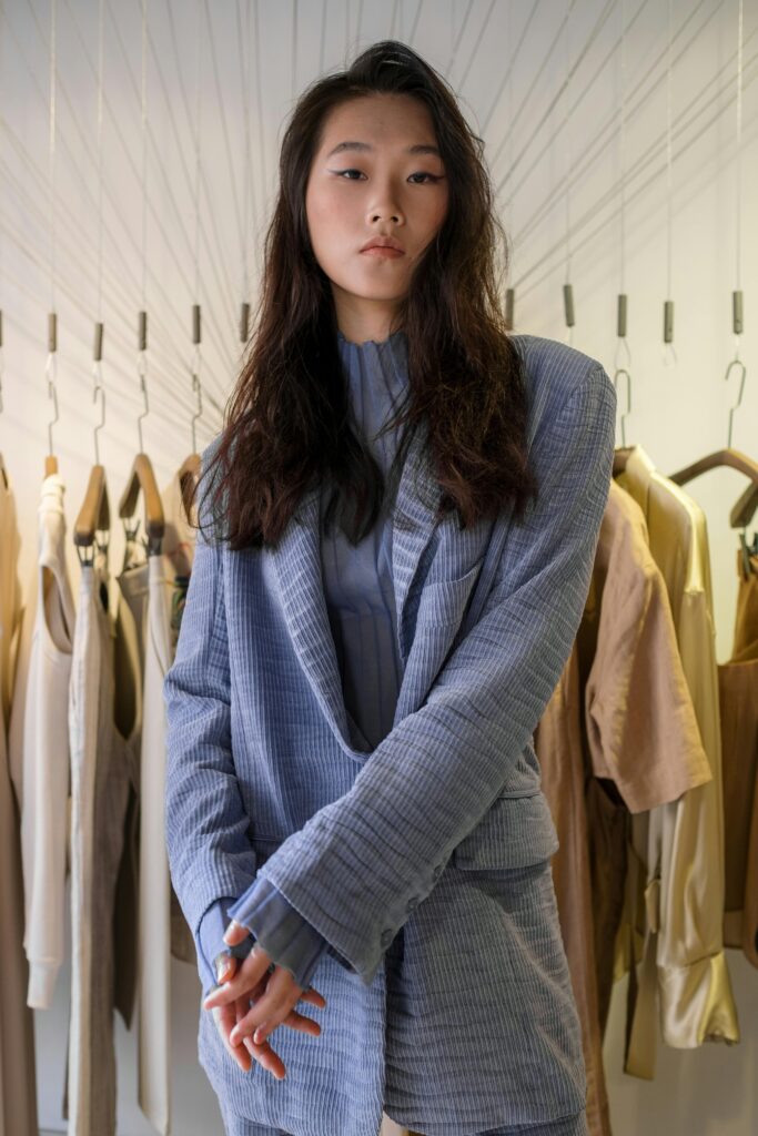 Fashionable young Asian woman in a stylish blazer posing in a boutique setting.